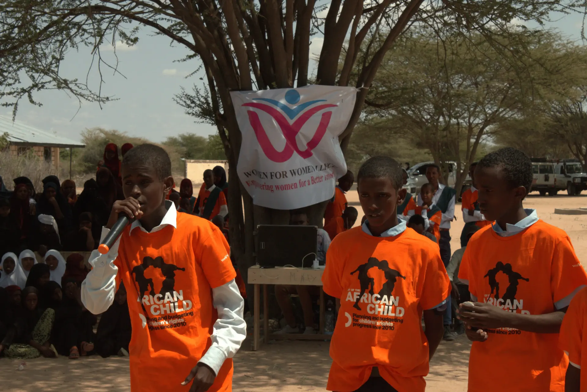 Young people in orange Day of the African Child t-shirts speaking at a community event